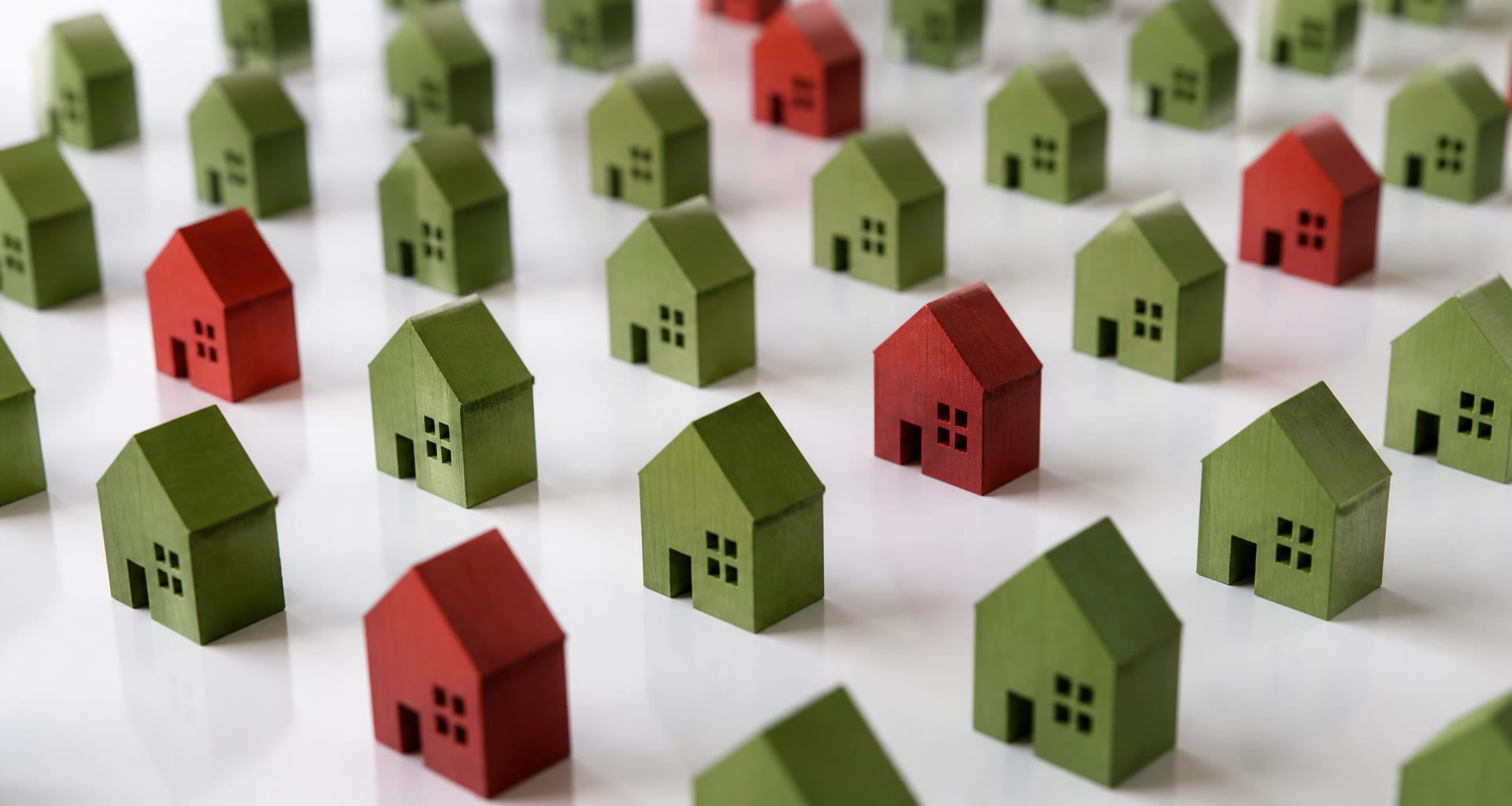 Rows of red model houses with a single green house